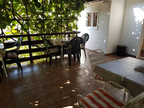 Natkrivena terasa sa stolovima i stolicama, okružena zelenilom. - image 8