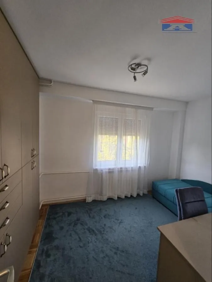 Small bedroom with a wardrobe, a bed, and a window with curtains.