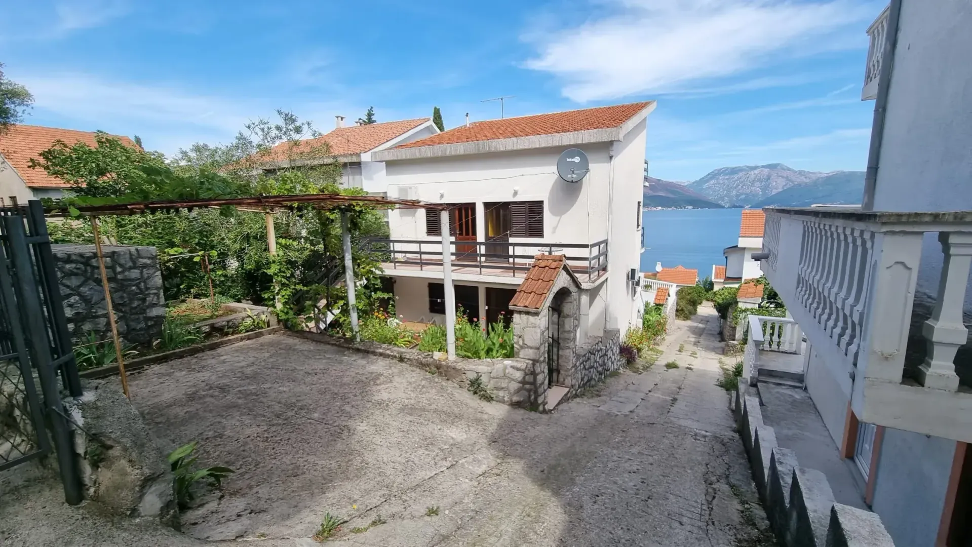 Pogled na dvorište i fasadu kuće sa pogledom na more.