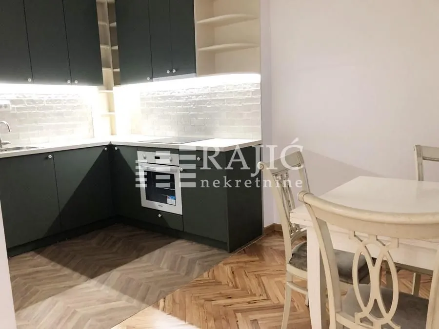 Modern kitchen with dark cabinetry and a dining table.