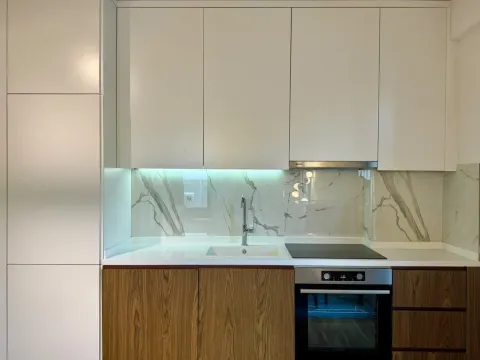 Modern kitchen with white upper cabinets, wooden lower cabinets, and a marble backsplash. - image 12