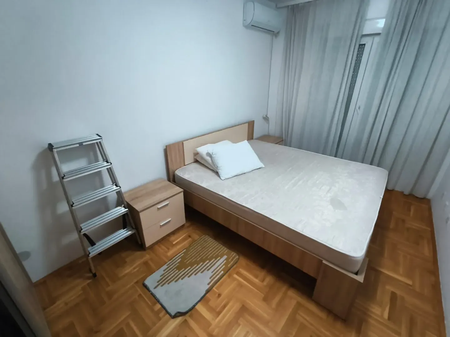 A bedroom with a double bed, nightstands, and wooden flooring.