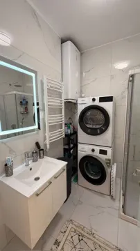Modernly equipped bathroom with a washbasin, shower cabin, and laundry machines. - image 10