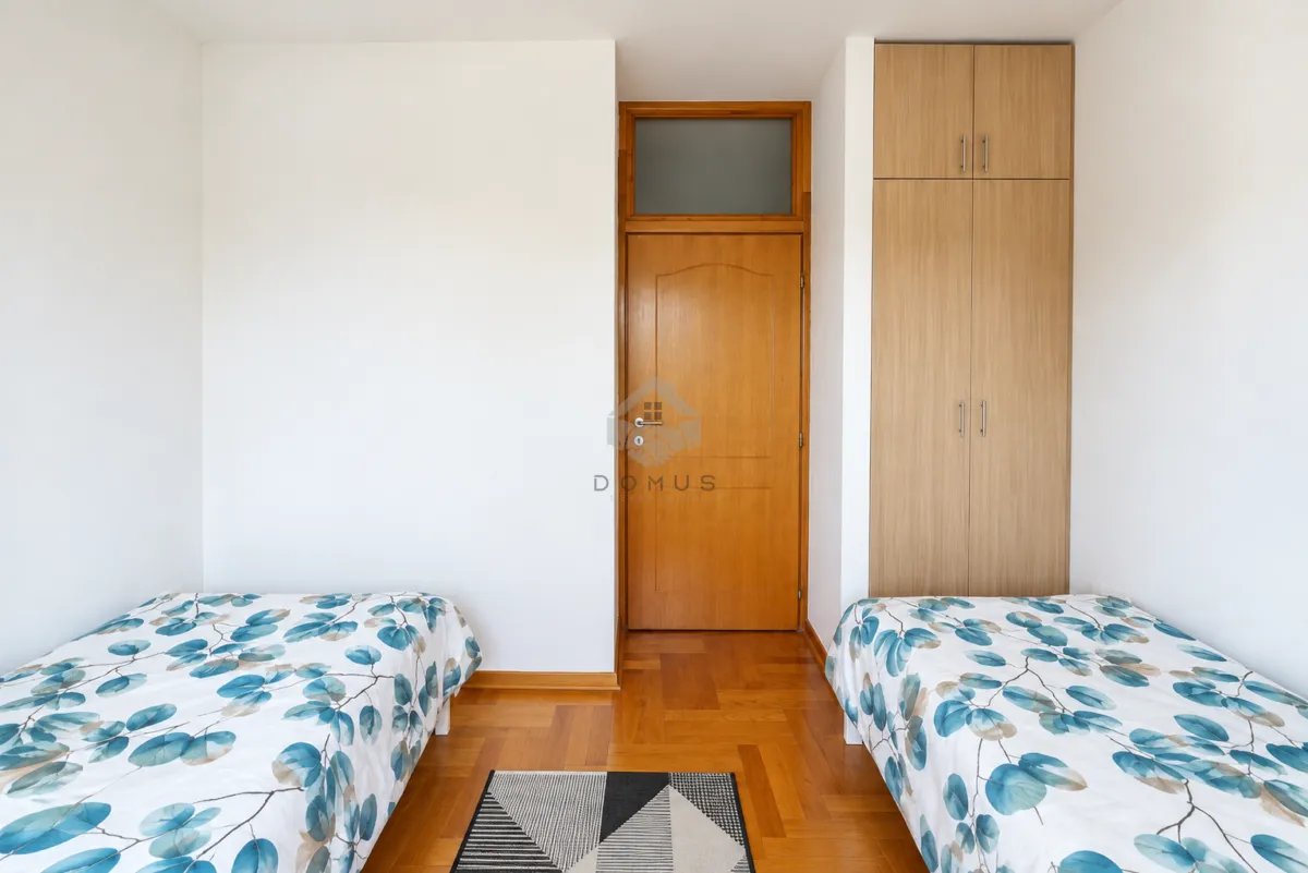 Bedroom with two beds, wooden wardrobe, and parquet flooring.