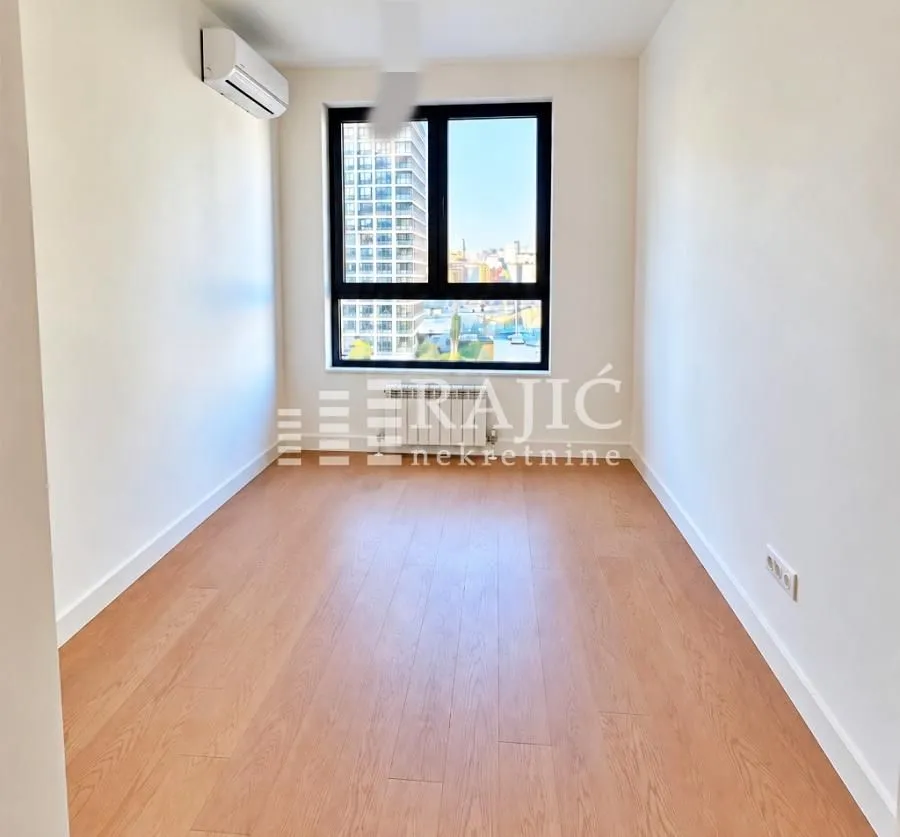 Empty room with wooden flooring and a window.