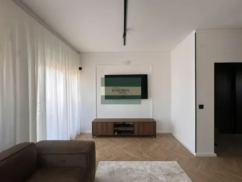 Dnevna soba sa TV komodom, drvenim podom i velikim prozorom sa belim zavesama. - image 8