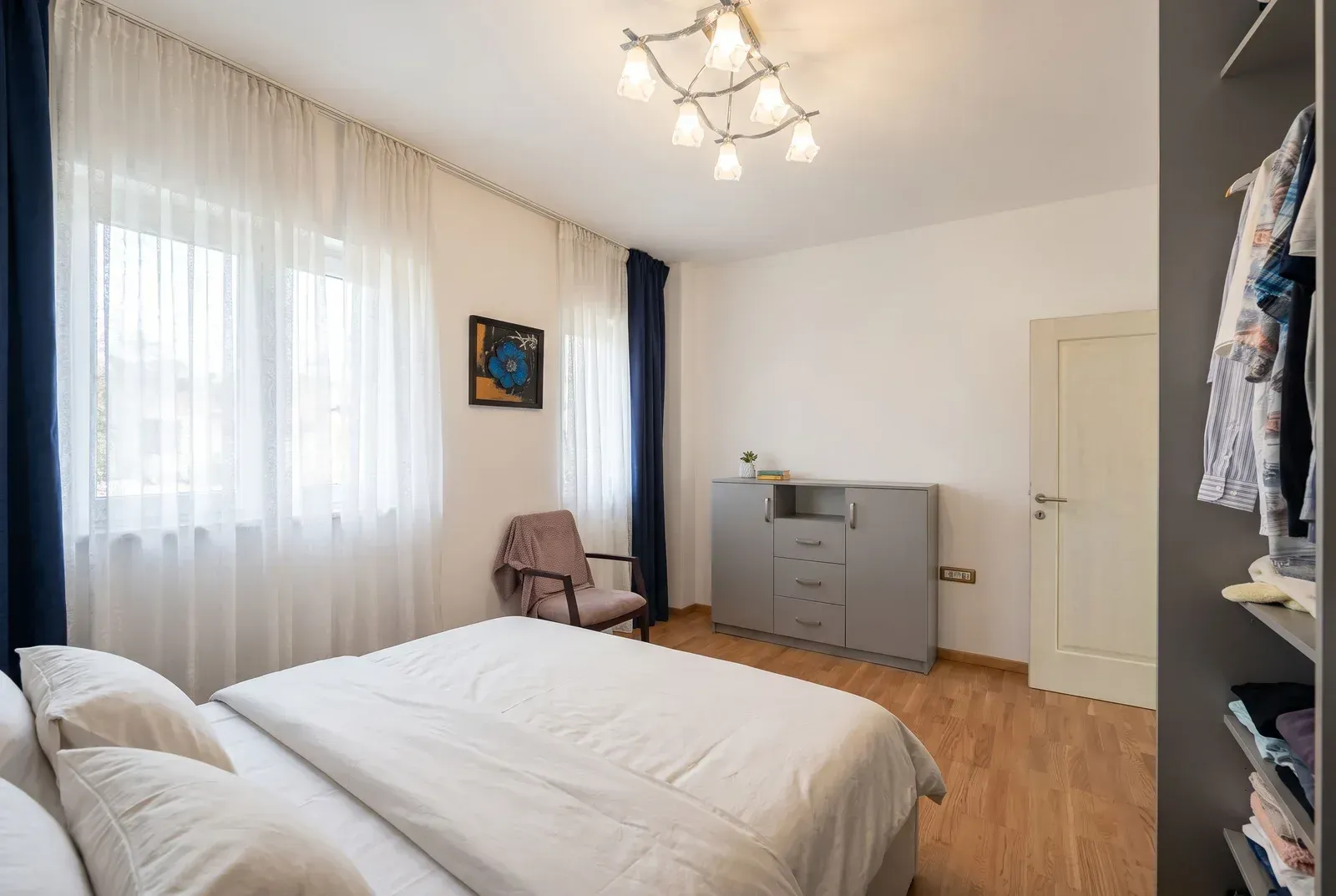 Bright bedroom with a double bed, wardrobe, and a large window.