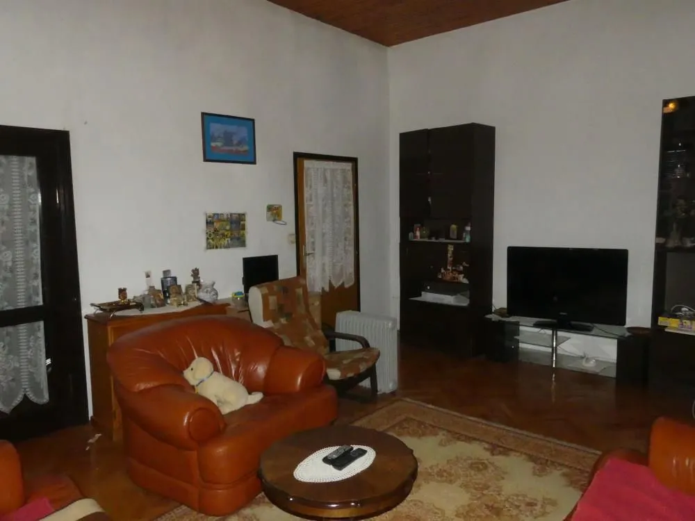Living room with sofa set, television, and wooden furniture.