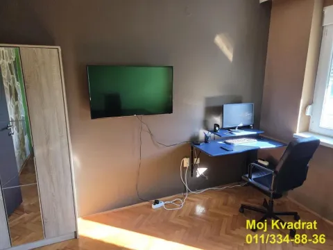 Radni kutak sa stolom, računarom i televizorom na zidu. - image 7