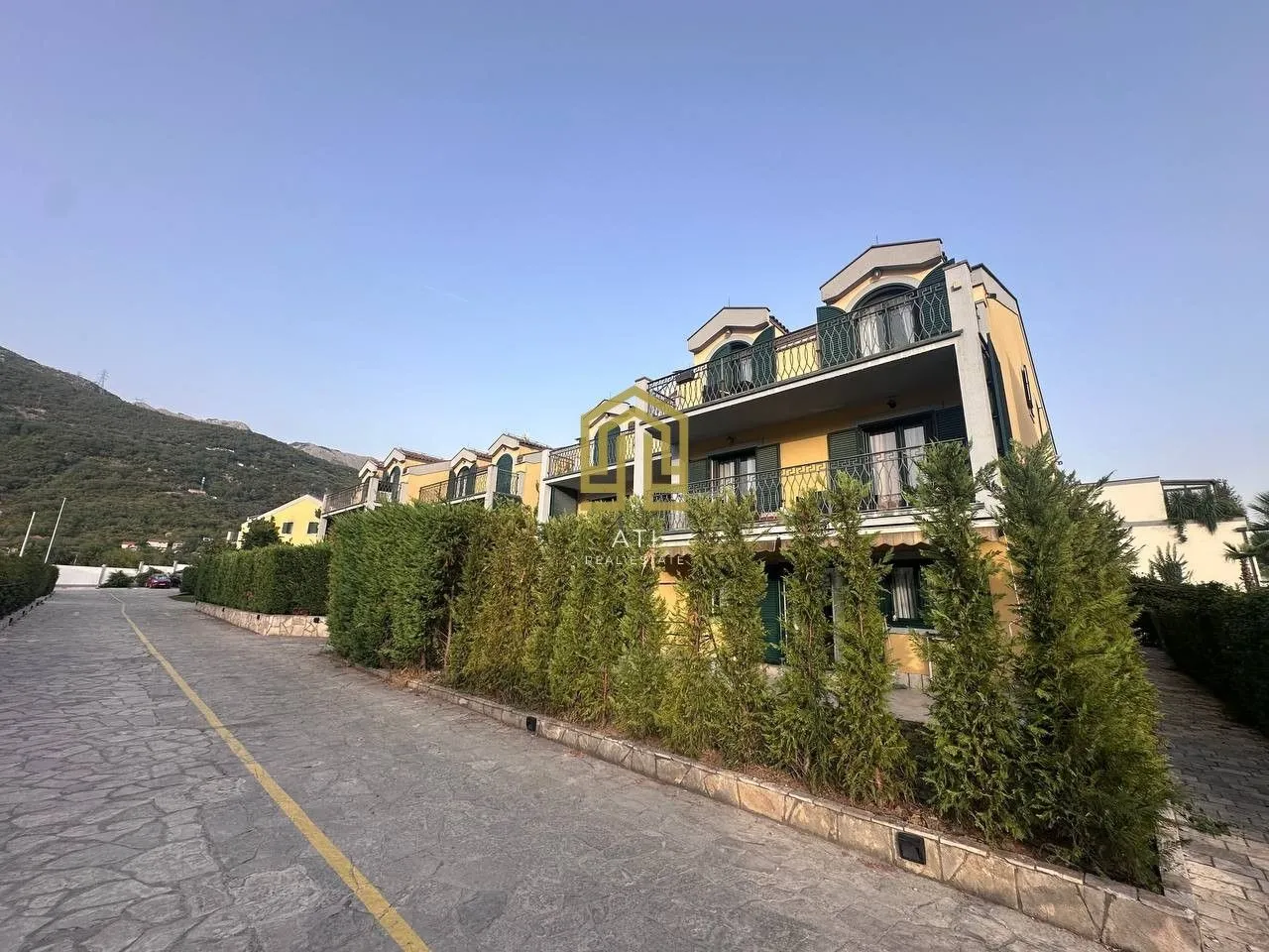Pogled na spoljašnjost zgrade sa uređenim dvorištem i prilazom.