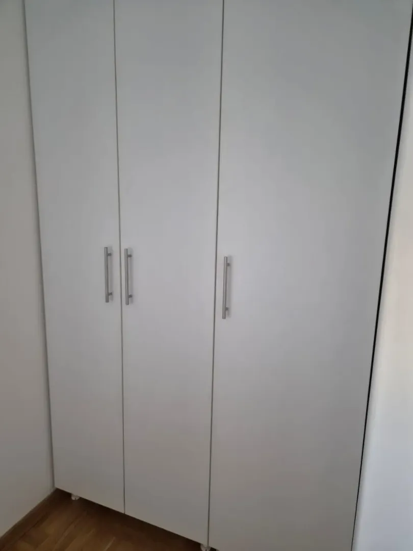 Beli garderober sa metalnim ručkama u sobi.