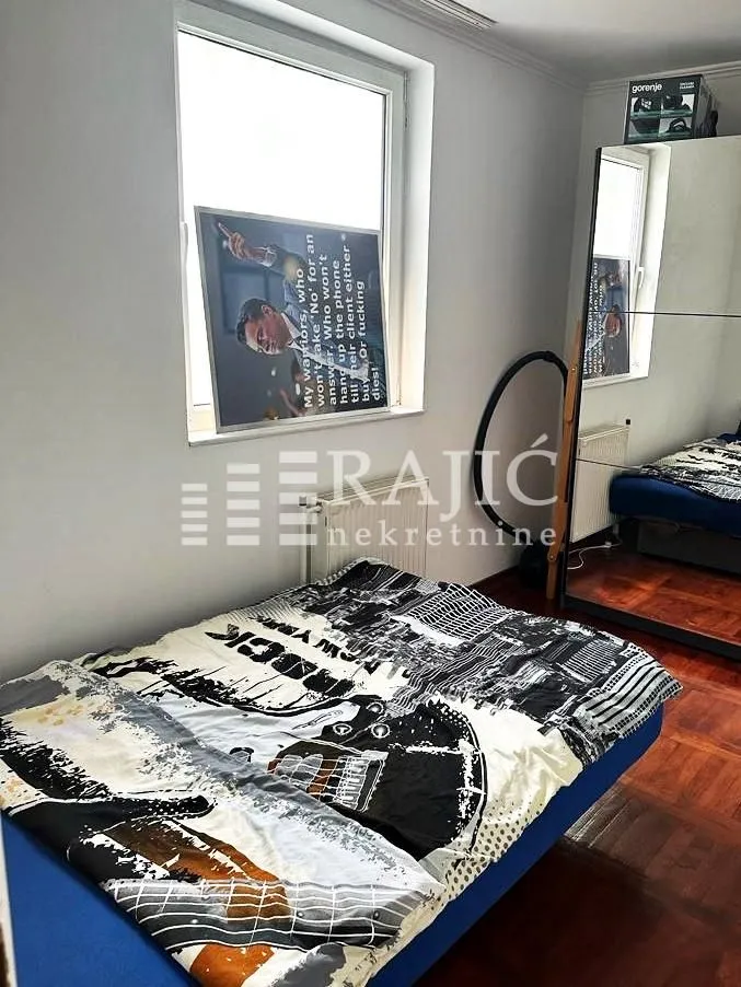 Small bedroom with a bed and a large mirror.