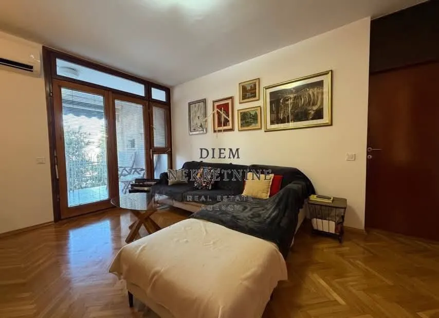 Dnevna soba sa garniturom, stočićem i parketom na podu.