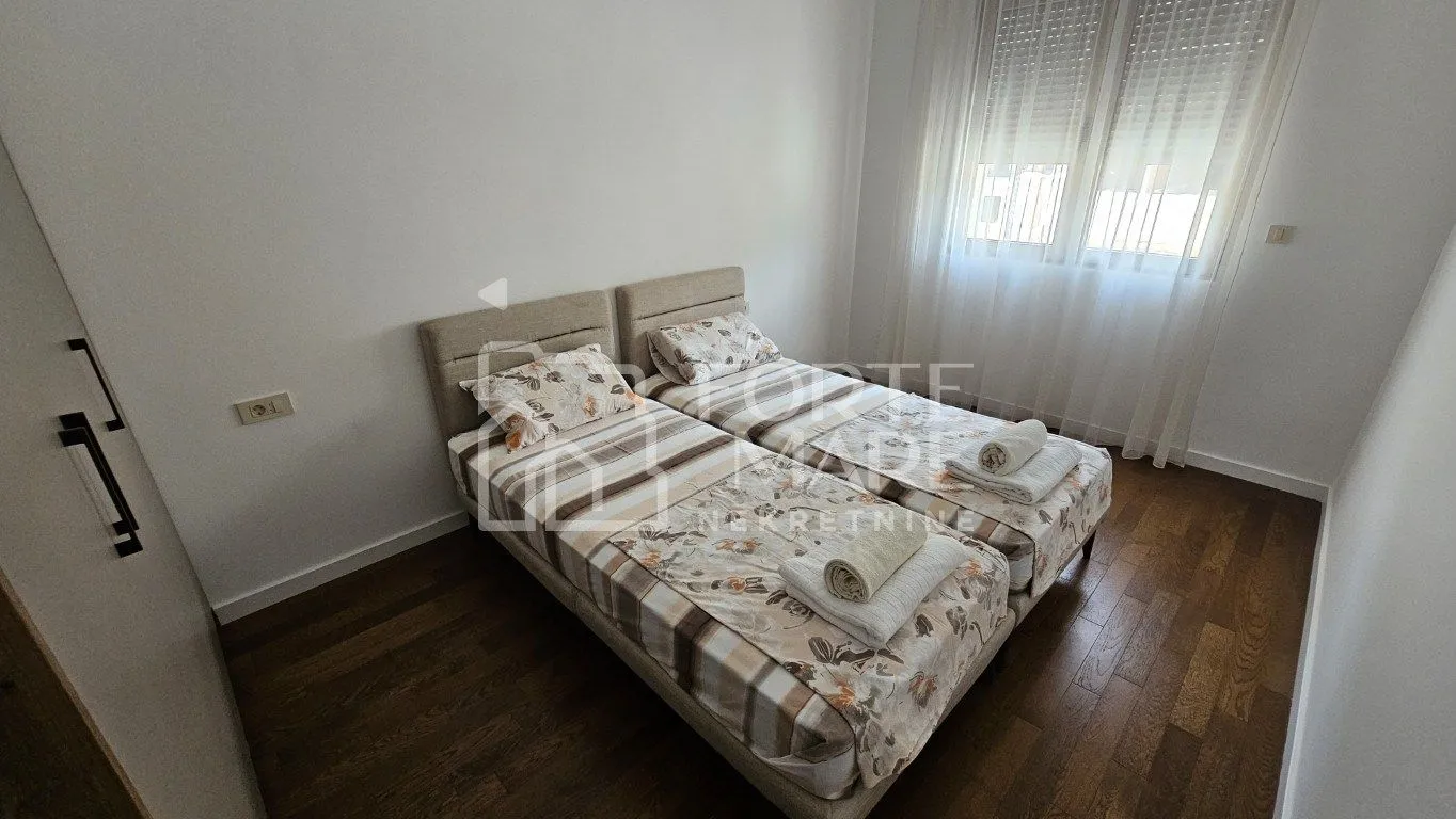 Spavaća soba sa dva odvojena kreveta i drvenim podom.