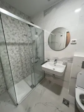 Modern bathroom with a shower cabin and a round mirror. - image 6
