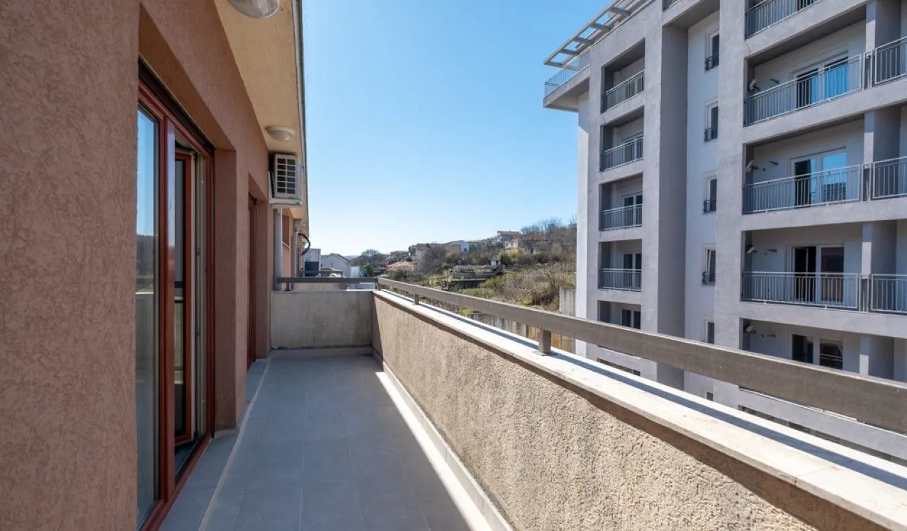 Dugački balkon sa pogledom na susjednu zgradu i okolinu.