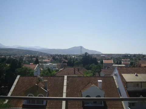 Pogled sa terase na krovove kuća i planine u daljini. - image 8