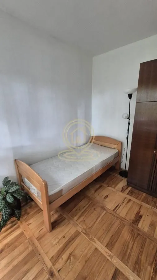 Manja spavaća soba sa drvenim krevetom i ormanom.