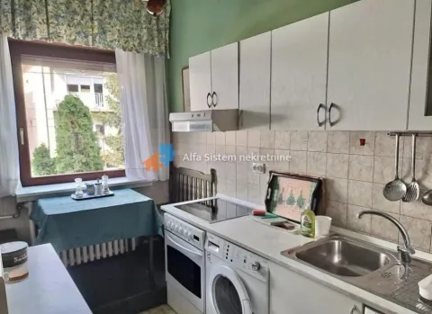Small kitchen with white cabinets, sink, stove, and a dining table by the window. - image 12