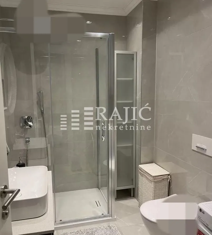 Modern bathroom with a shower cabin, washbasin, and toilet fixtures.