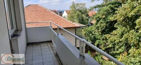 Manji popločani balkon sa metalnom ogradom i pogledom na zelenilo i okolne krovove. - image 12