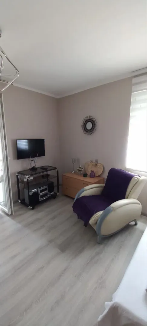 Living room with an armchair, chest of drawers, and TV.