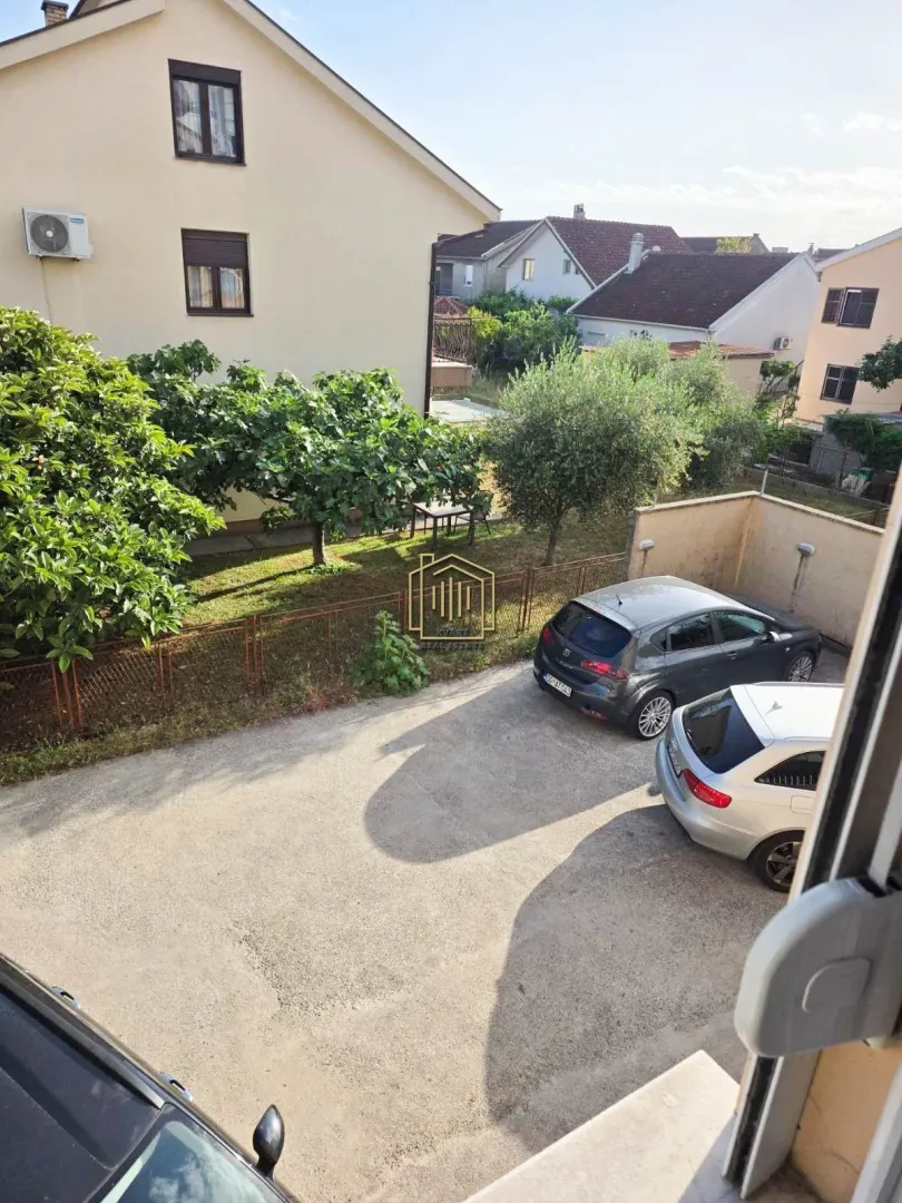 Pogled sa prozora na dvorište i parking ispred zgrade.