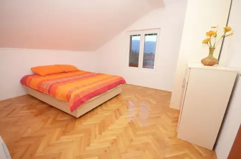 Spavaća soba sa bračnim krevetom, drvenim parketom i kosim plafonom. - image 9