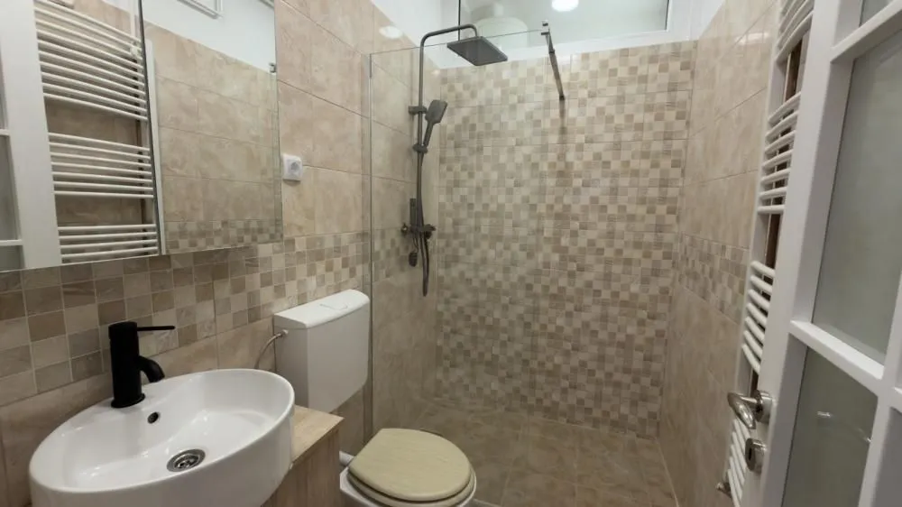 Kupatilo opremljeno umivaonikom, WC šoljom i tuš kabinom.
