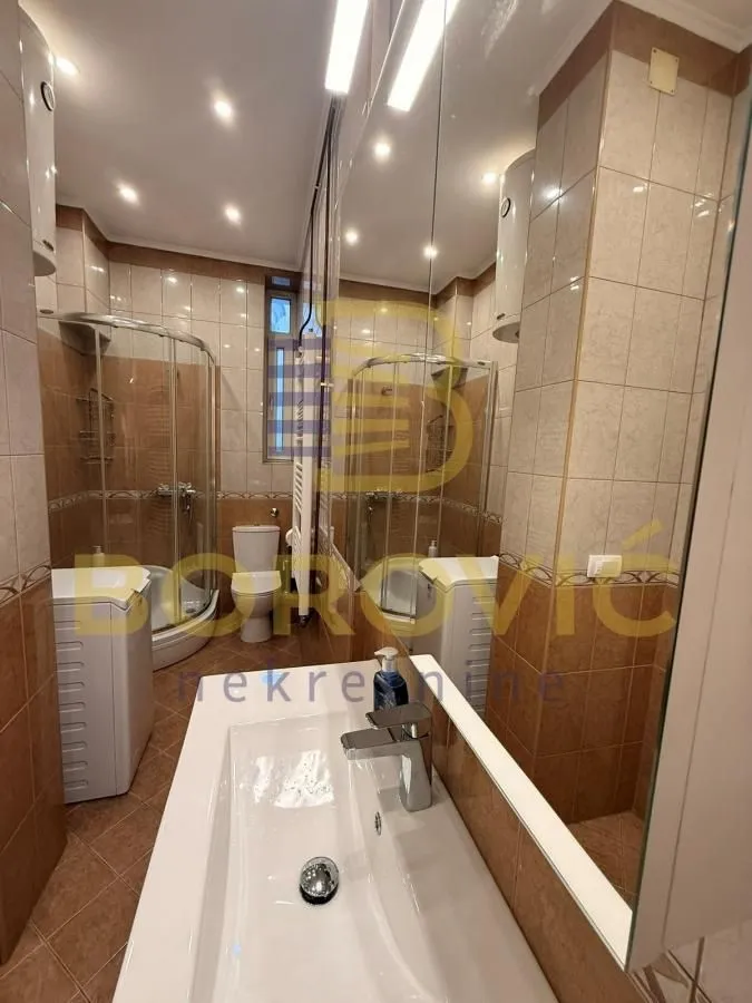 Kupatilo opremljeno umivaonikom, tuš kabinom, WC šoljom i veš mašinom.