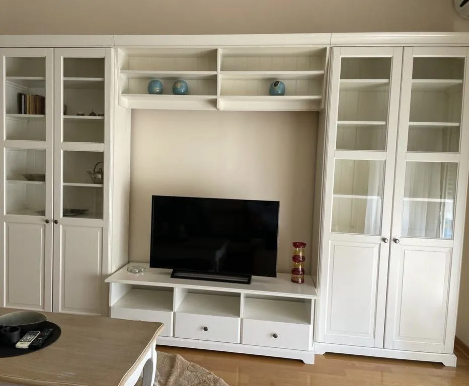 White TV unit with shelves and cabinets in a living room.