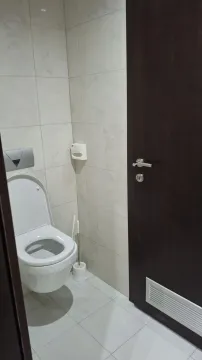 Small toilet with light tiles and a dark door. - image 13
