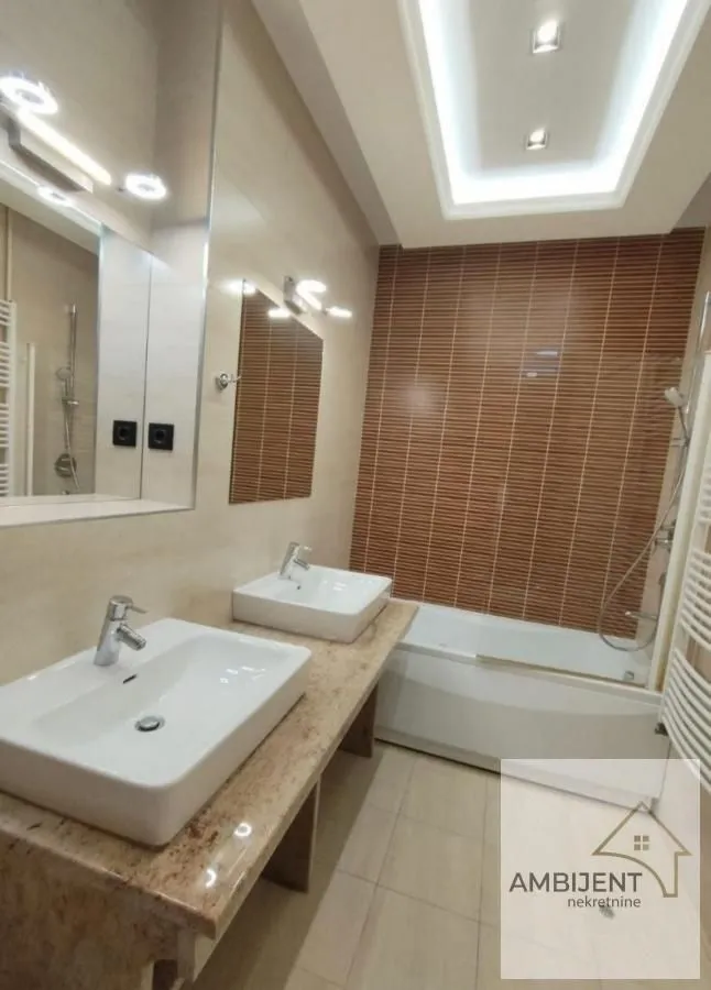 Modern bathroom equipped with two washbasins and a bathtub.