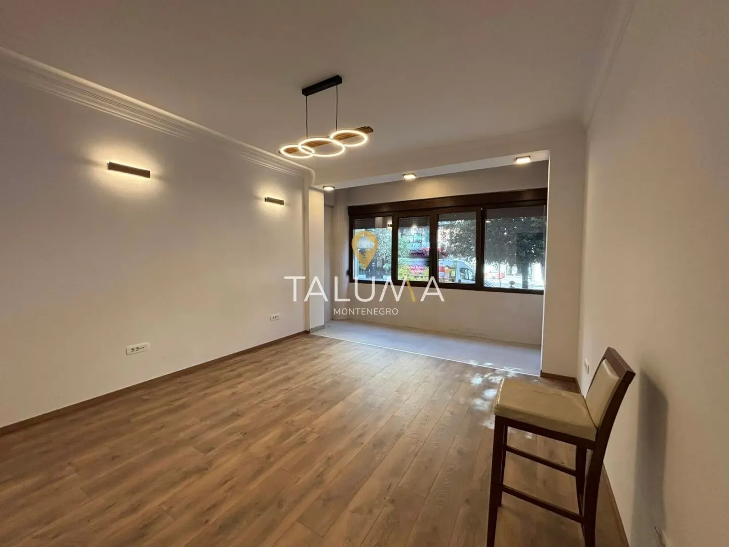 Empty living room with wooden flooring and modern lighting.