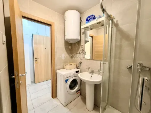 Smaller bathroom with a walk-in shower, washbasin, and washing machine. - image 7