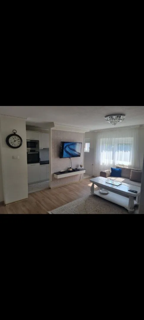 Bright living room with a seating set, coffee table, and wall-mounted TV.