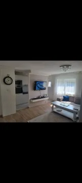 Bright living room with a seating set, coffee table, and wall-mounted TV. - image 12