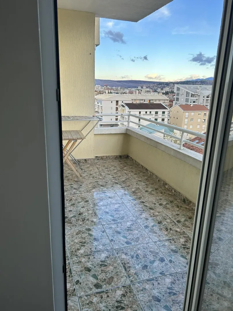 Prostrana terasa sa pločicama i pogledom na grad.