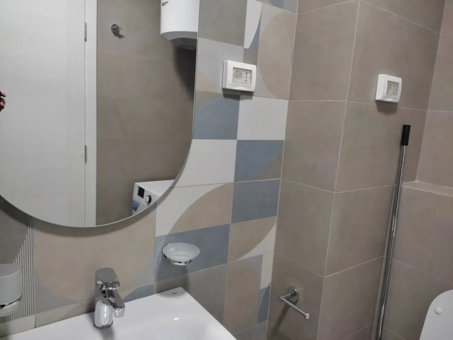 Modern ceramic tiles in a bathroom with a sink and a mirror.