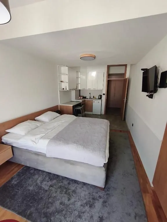 Master bedroom with a double bed and a small kitchen in the corner.