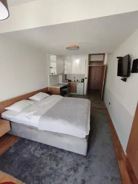 Master bedroom with a double bed and a small kitchen in the corner. - image 12