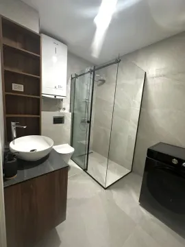 Modern bathroom with a walk-in shower, washbasin, and washing machine. - image 9