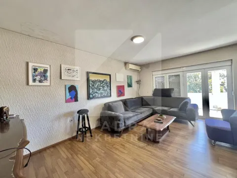 Living room with a sofa, coffee table, and paintings on the wall. - image 2