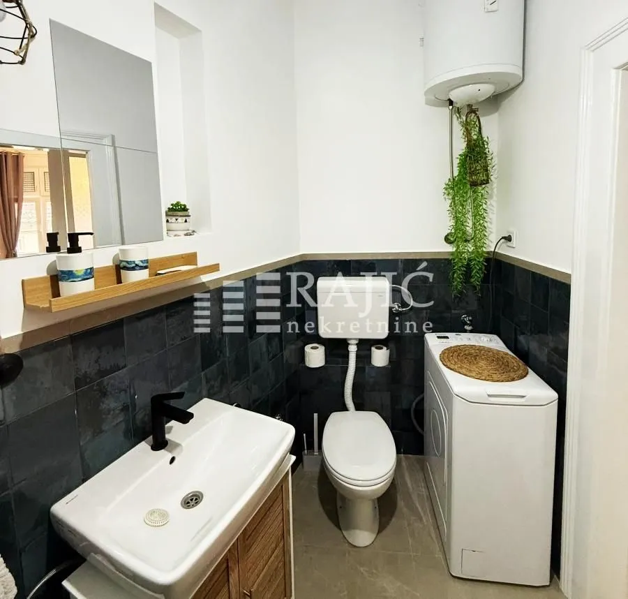 Small bathroom with a sink, toilet, water heater, and washing machine.