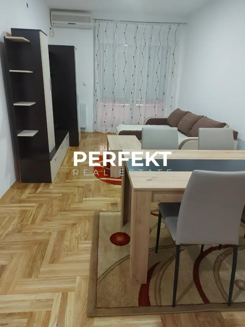 Living room with sofa, dining table, and parquet flooring.