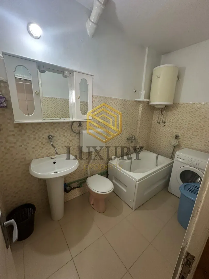 Smaller bathroom with a bathtub, washbasin, toilet, and washing machine.