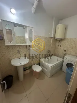 Smaller bathroom with a bathtub, washbasin, toilet, and washing machine. - image 6