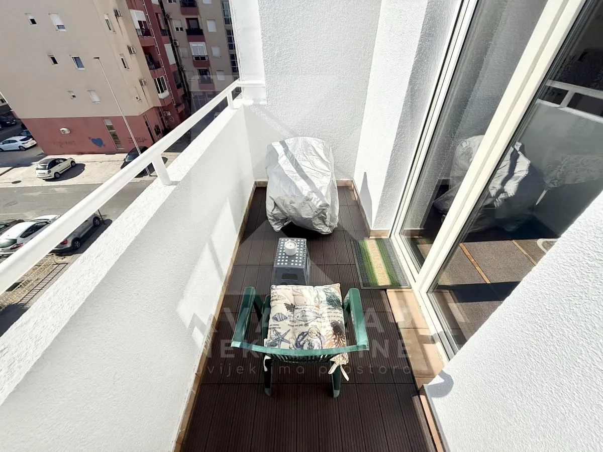 Small furnished balcony with chairs and street view.