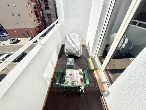 Small furnished balcony with chairs and street view. - image 10