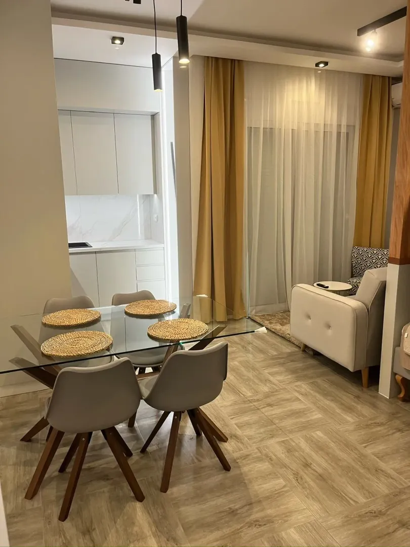 Moderan dnevni boravak sa trpezarijom i ugradnom kuhinjom u pozadini.
